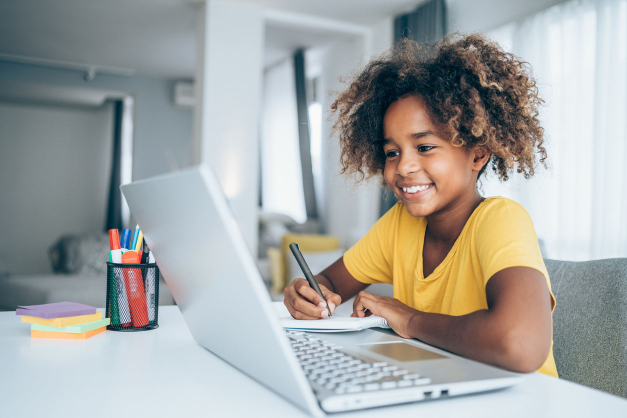 A cheerful student smiling while writing during a tutoring lesson